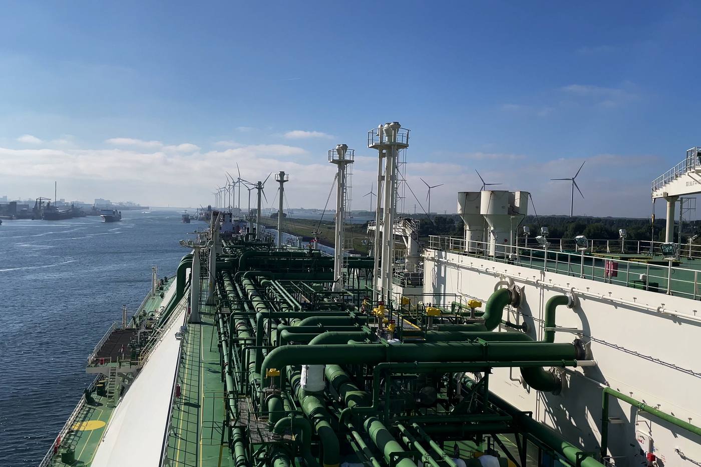 LNG-tanker met een dek vol groene leidingen die een Nederlandse haven binnenvaart