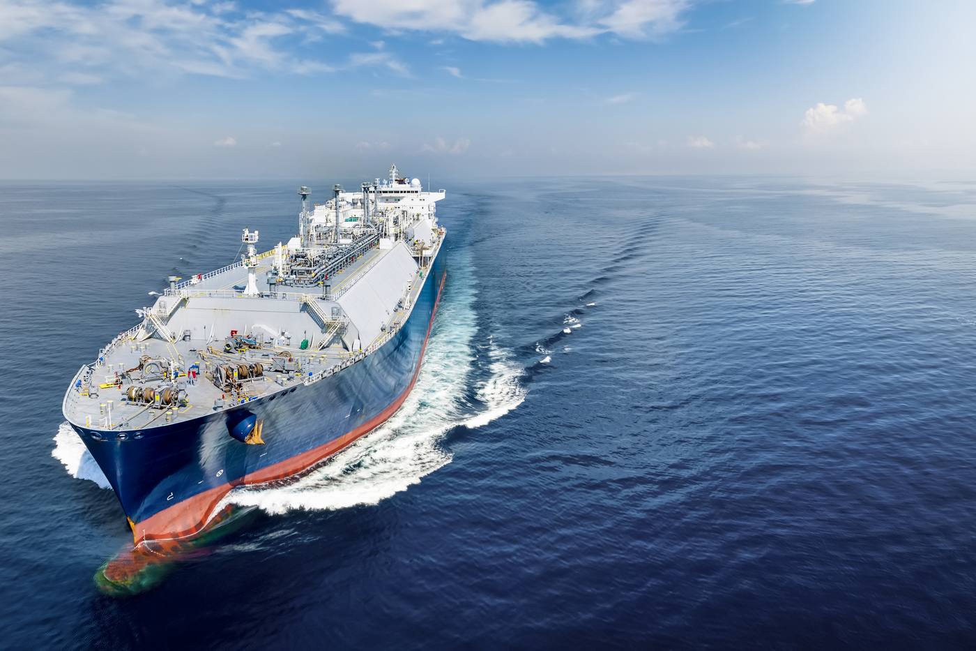 LNG tanker at full speed across a calm blue sea, seen from the front