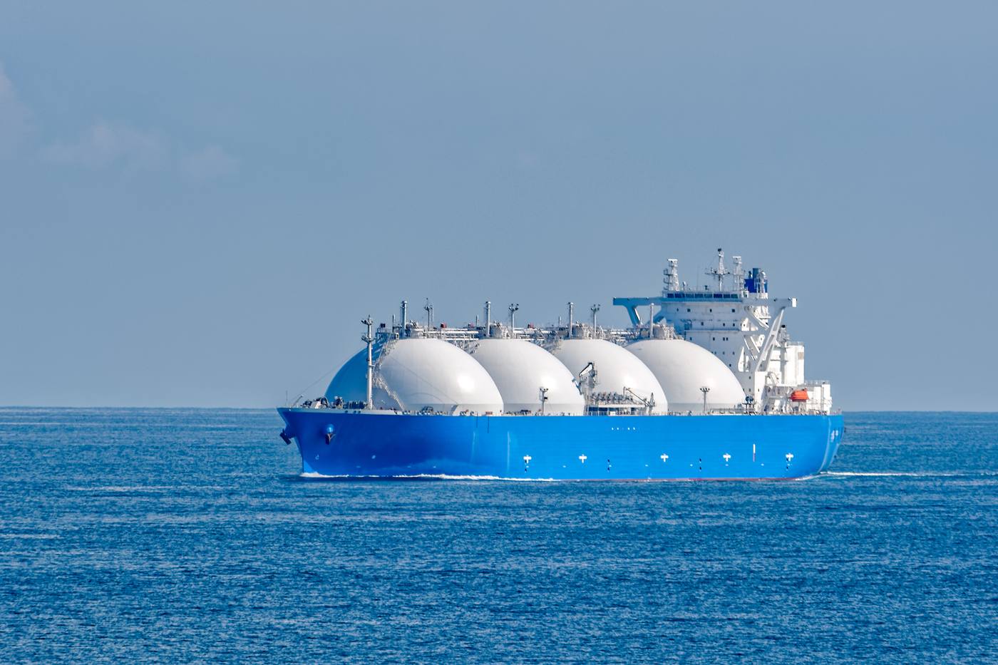 Blauwe LNG-tanker met vier witte boltanks vaart op open zee