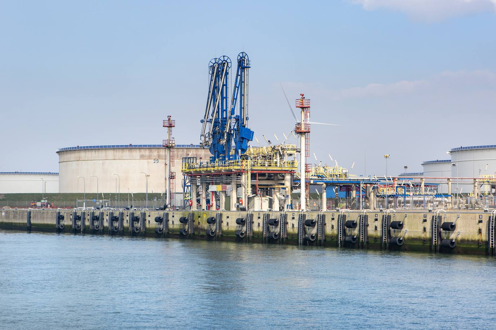 LNG-terminal op de Maasvlakte in Rotterdam, met blauwe laadarmen op de steiger en grote witte opslagtanks